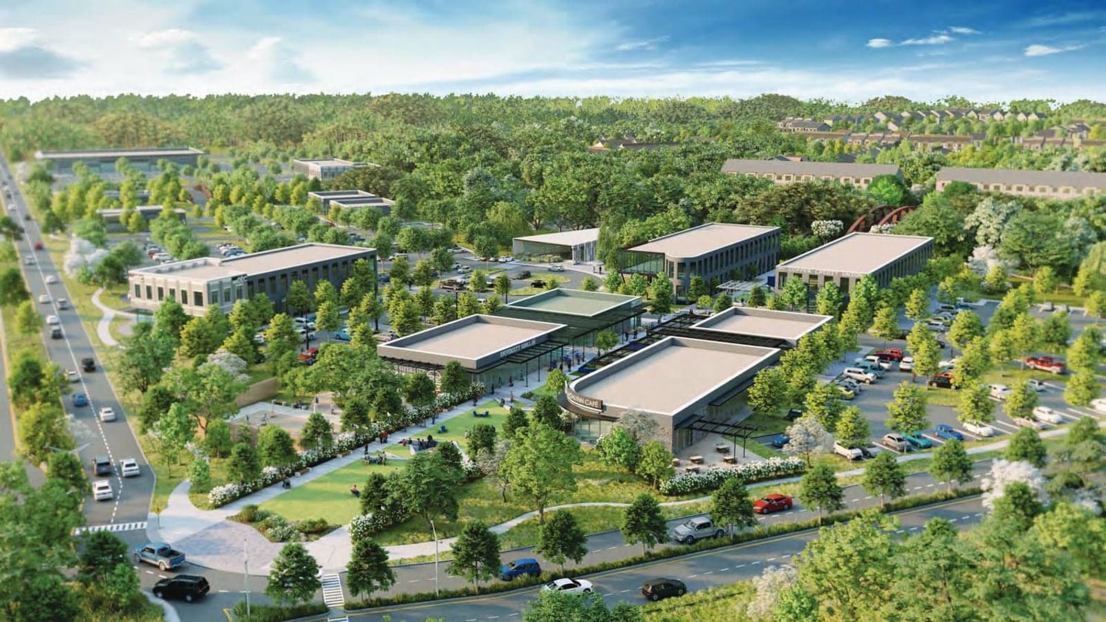 Aerial rendering of low commercial buildings around a lawn and parking areas among trees, with a divided road on the left and rows of residential buildings in the distance