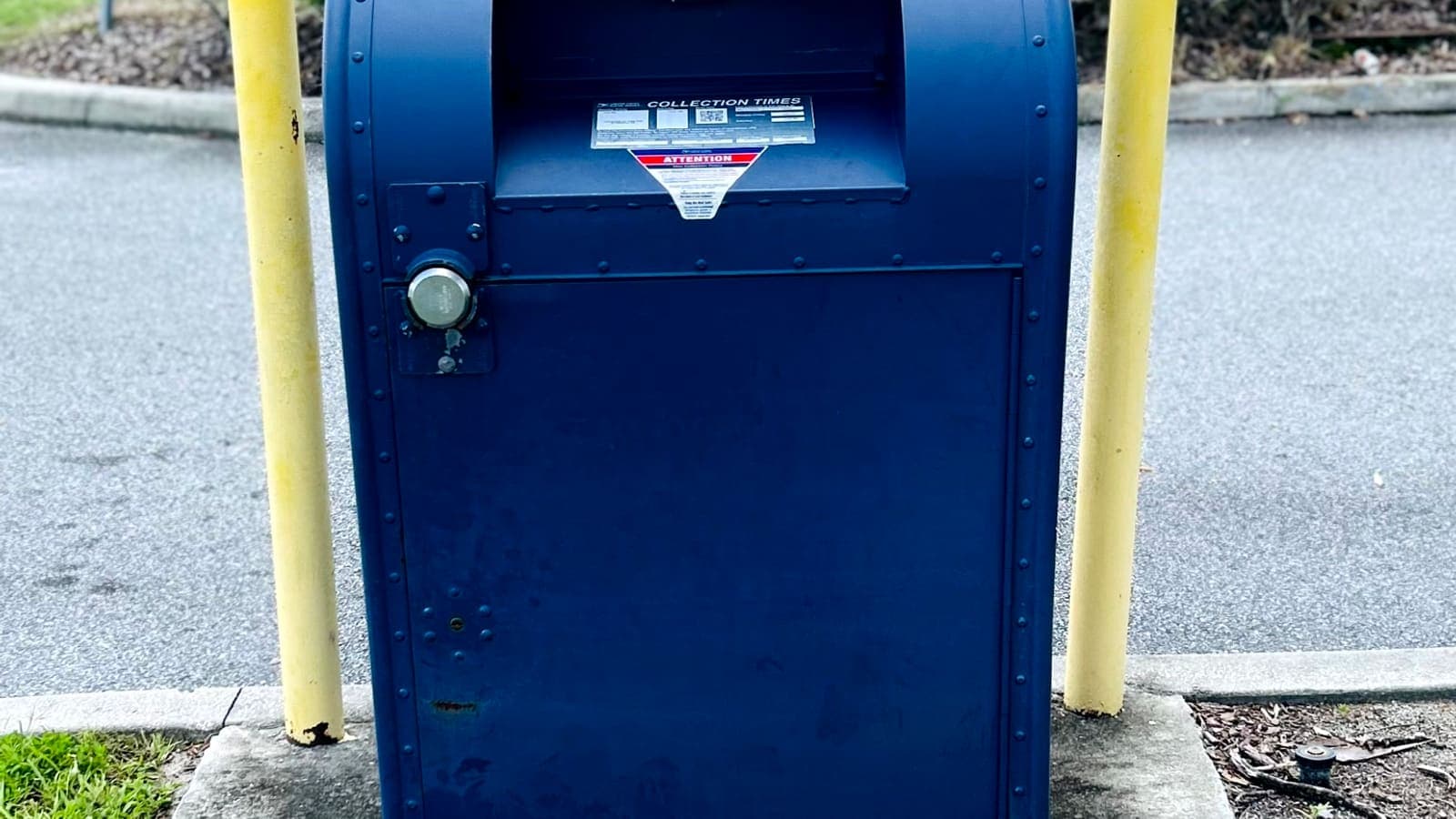 A blue USPS collection mailbox outside a post office