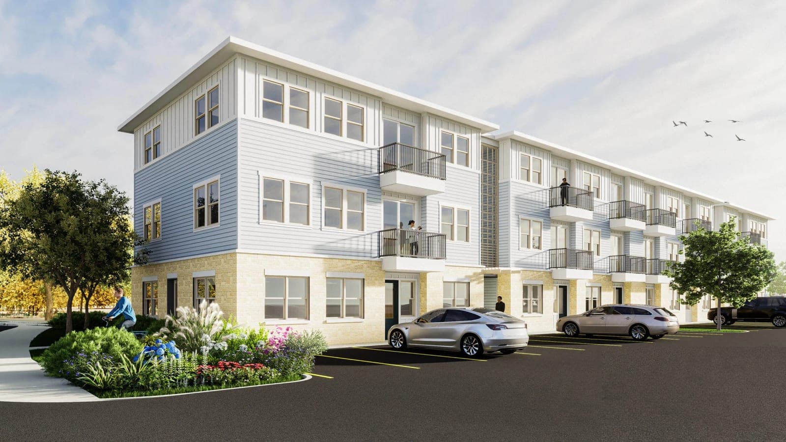Rendering of a three-story apartment building with pale blue siding over a tan brick ground floor, balconies with dark railings and cars parked in front