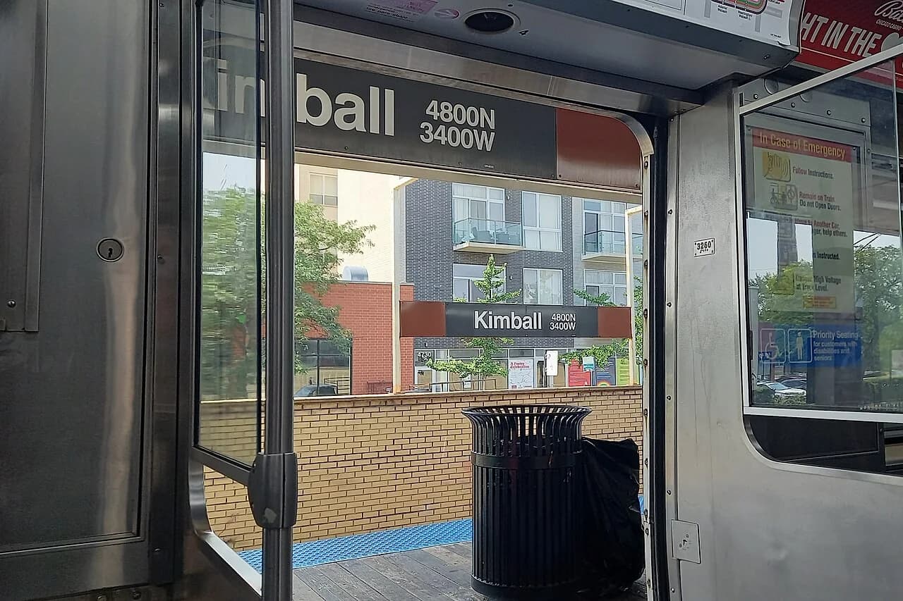 Kimball station and nearby apartments through a CTA train doorway in 2025.