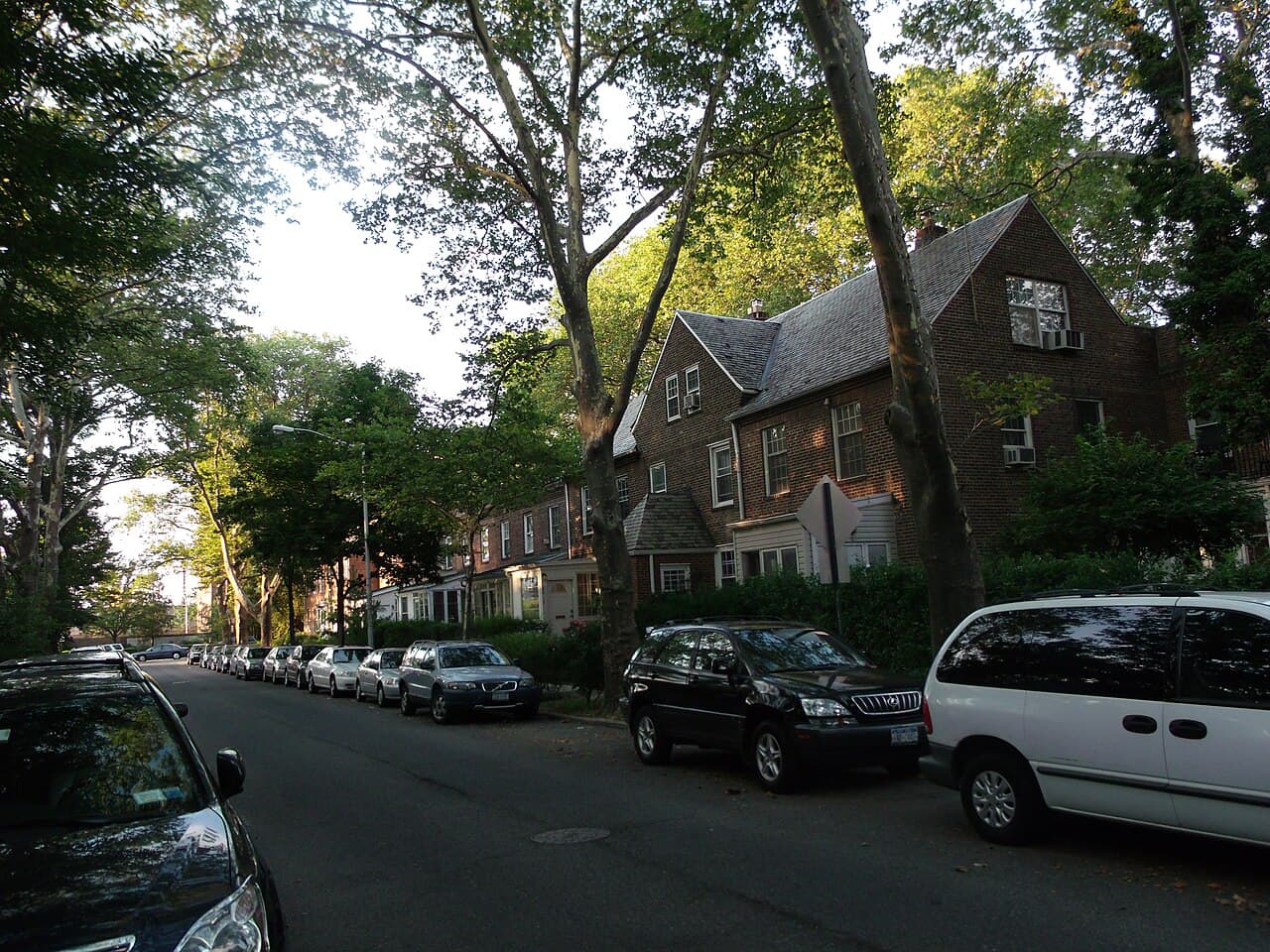 Brick homes, mature trees and parked cars in the Sunnyside Gardens Historic District.