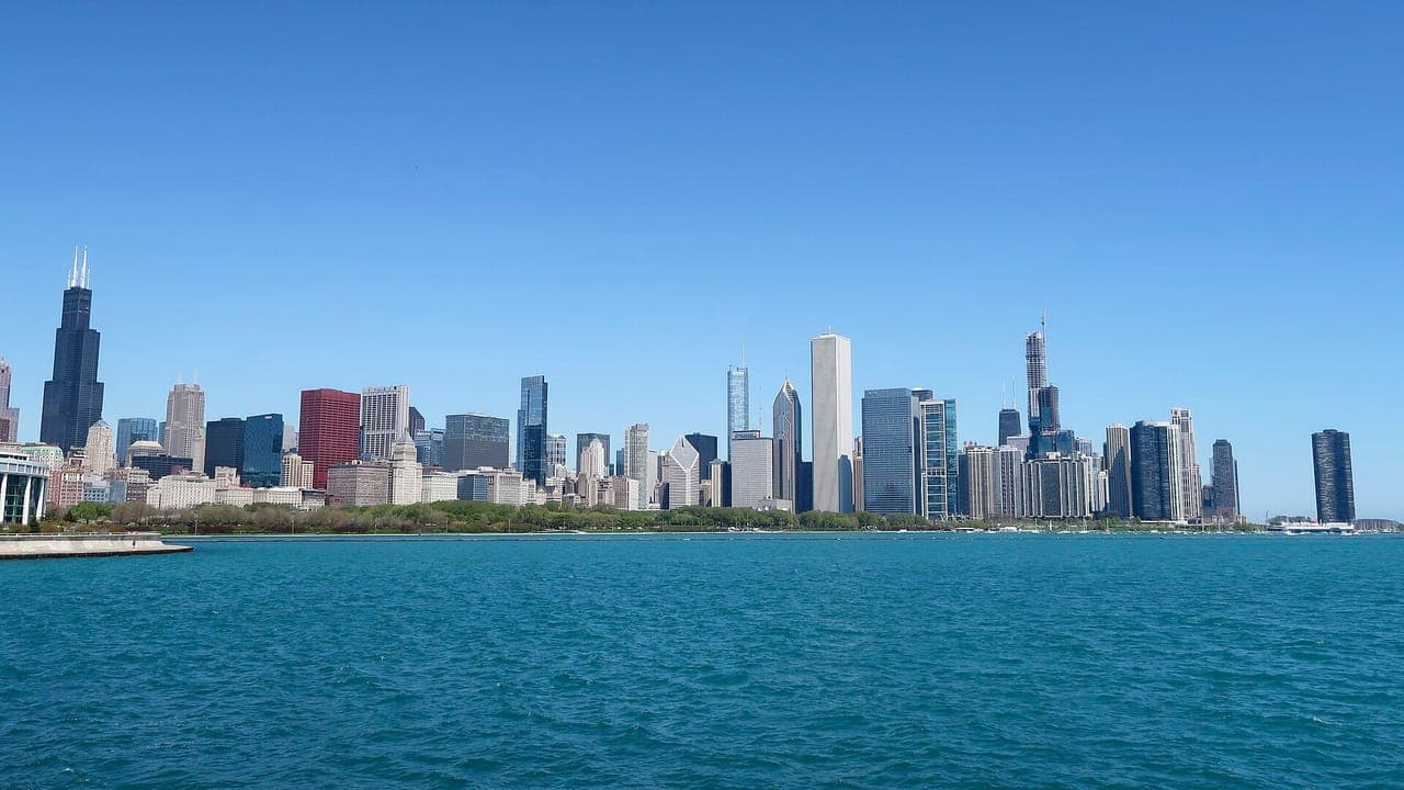 Downtown Chicago's skyline, with Willis Tower at the left, seen across blue-green Lake Michigan under a clear sky