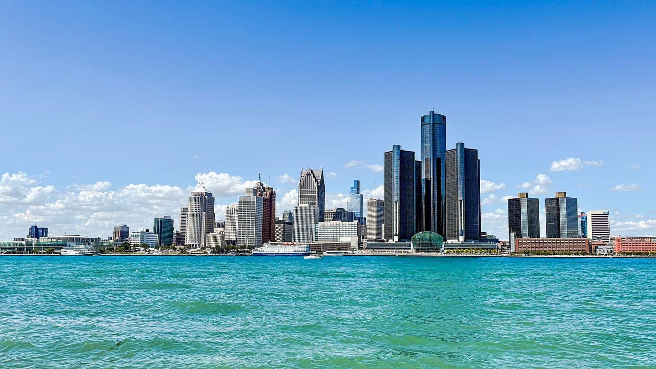 Downtown Detroit's skyline, with the dark glass towers of the Renaissance Center, seen across the turquoise Detroit River