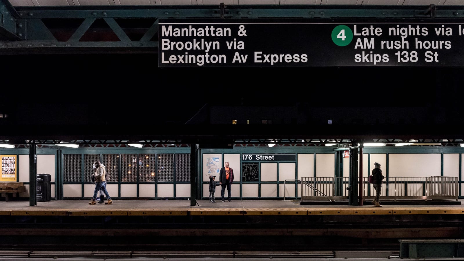 Photograph at night of an elevated subway platform with a sign reading 176 Street, green steel columns, white wall panels, a few people waiting or walking, and a large overhead sign reading Manhattan and Brooklyn via Lexington Av Express on the 4 line