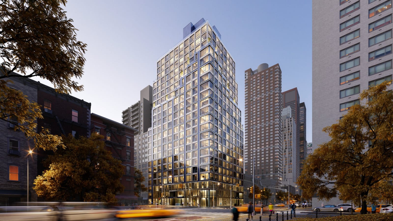 Rendering at dusk of a 23-story tower on a street corner with a grid of large windows framed in thin blue lines, small terraces stepping up near the top, a glass base, blurred taxis in the street and autumn trees in the foreground