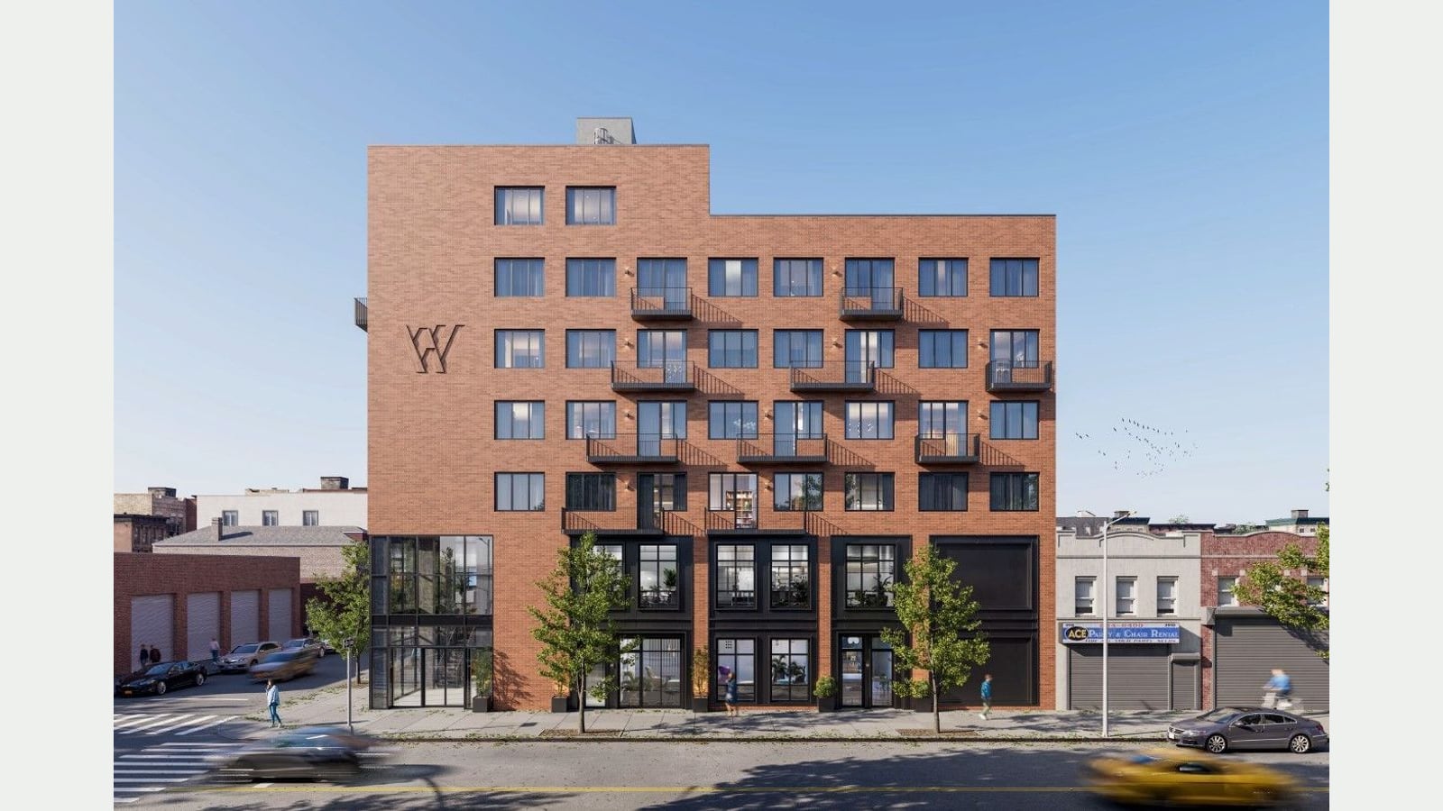Rendering of the long red-brick front of a seven-story building with rows of windows, black metal balconies, a W mark near the top left, a glass entrance at left, dark-framed shop windows at street level, young street trees, a neighboring one-story party rental store and blurred passing cars
