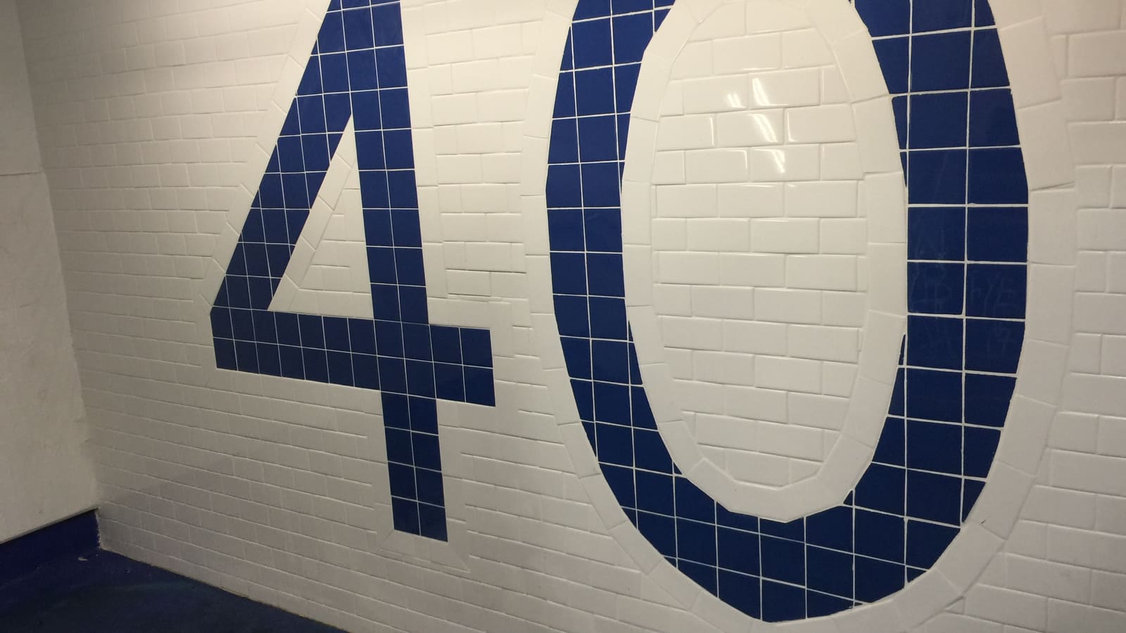 Large number 40 in dark blue tile set into a white tiled wall inside a subway station