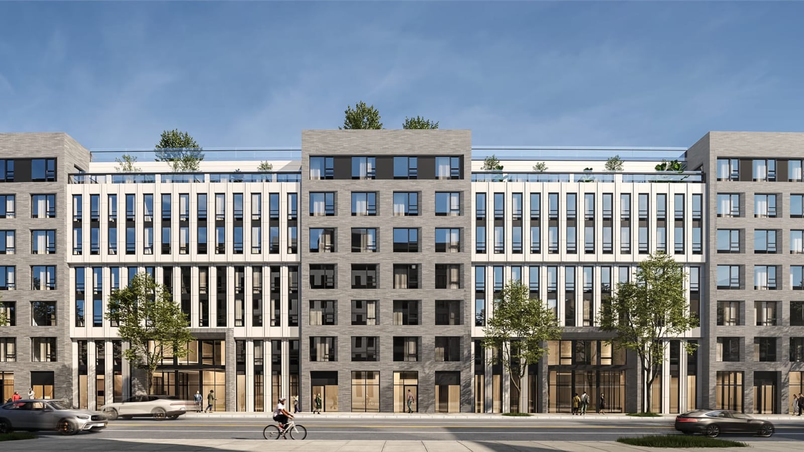 Rendering of the street front of a seven-story apartment building with three grey brick sections and two pale sections of tall narrow windows between them, planted roof setbacks, glass storefronts at street level, street trees, a cyclist and passing cars
