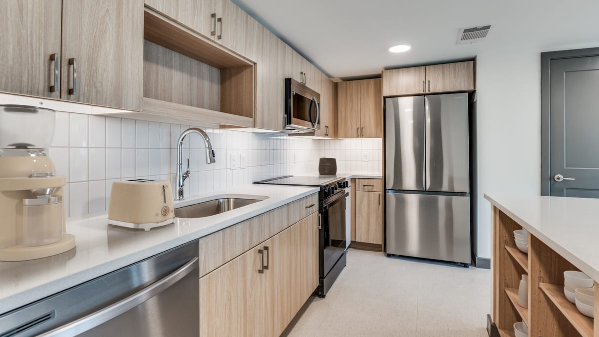 Kitchen with light wood cabinets, white counters and tile, a stainless-steel refrigerator, range, microwave and dishwasher