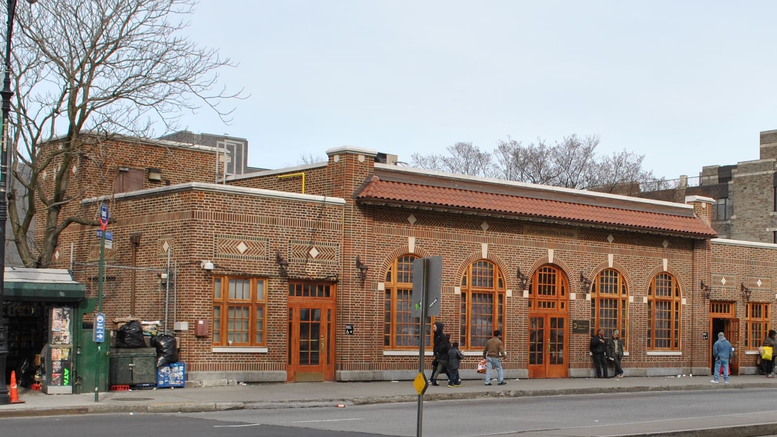 A low brick station building with arched windows and a tiled roof on East Fordham Road