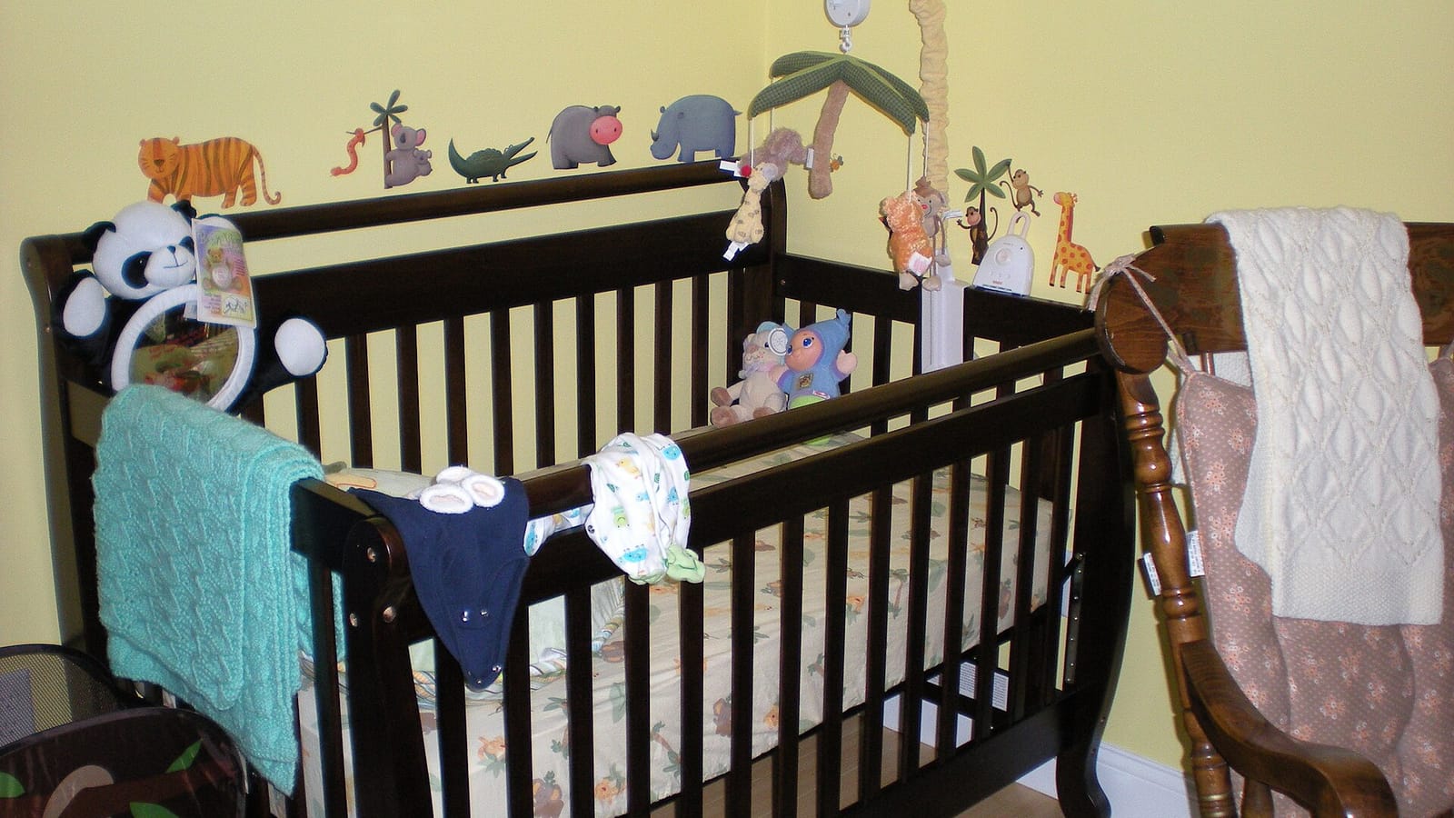 Empty wooden crib beside a wall with animal decorations