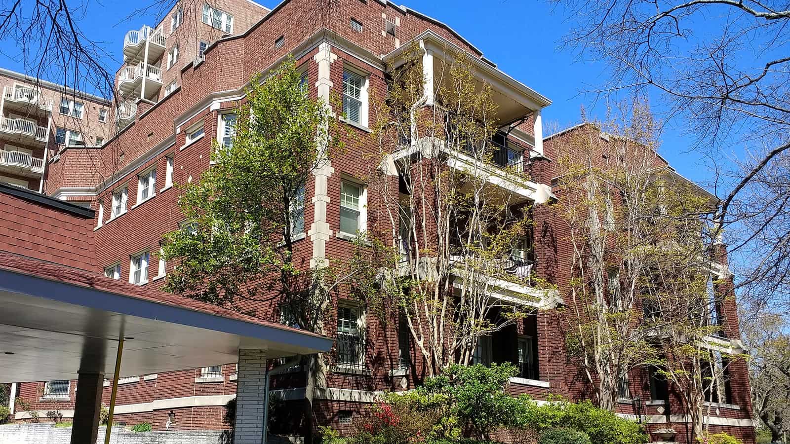 Brick apartment buildings with stacked open balconies supported by pale columns