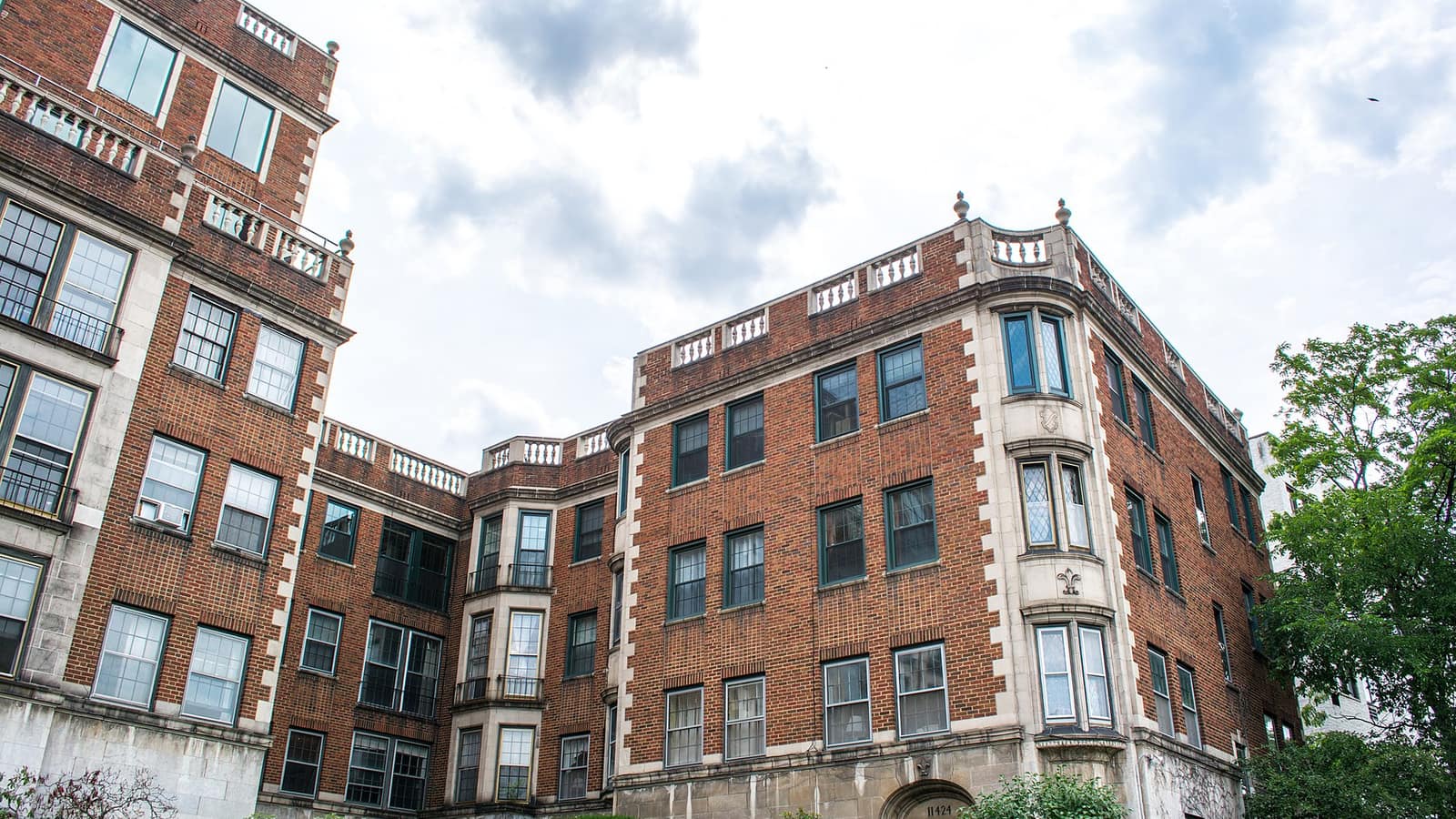 Red brick apartment wings with bay windows around a landscaped courtyard