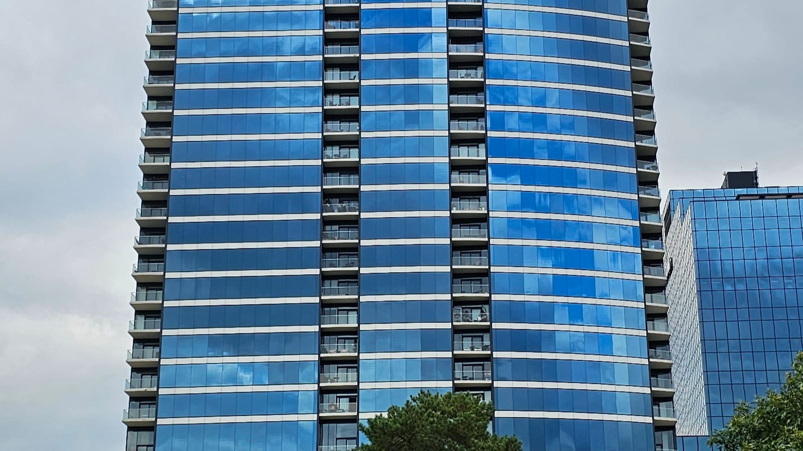 Blue glass residential tower with projecting balconies