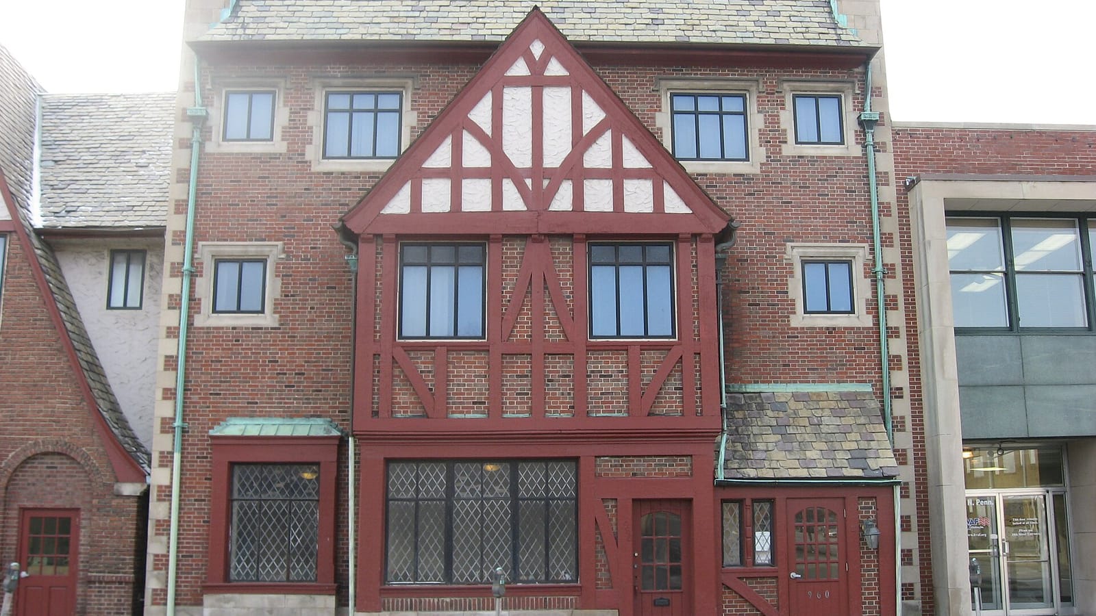 Apartment facade with patterned red timber framing, brickwork and steep roof sections