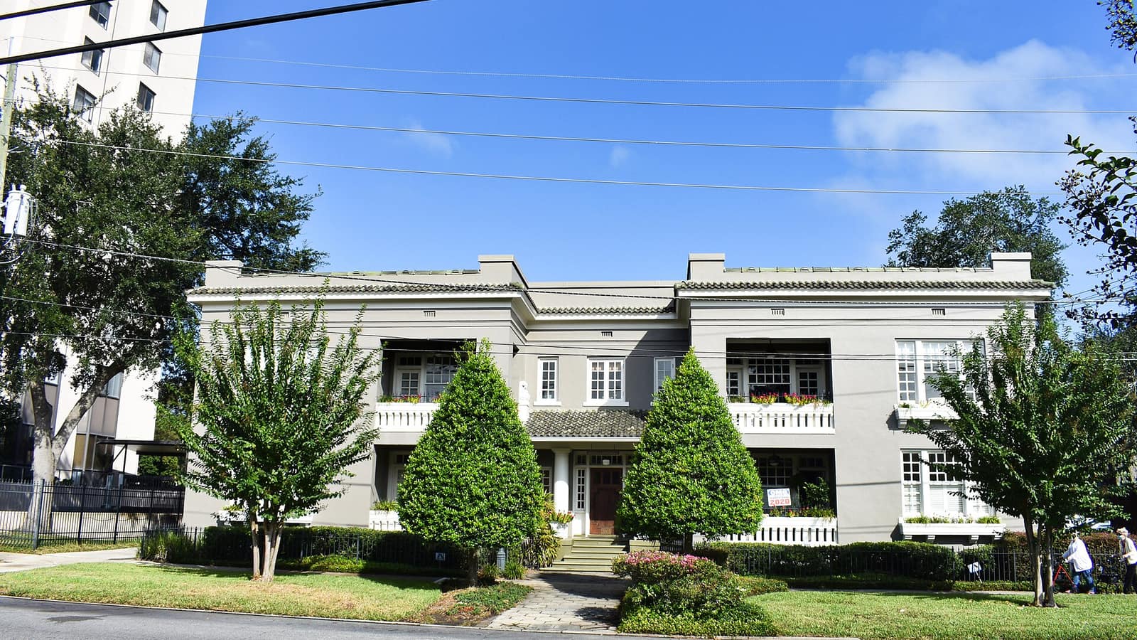Two-story pale apartment building with symmetrical windows and a central garden path