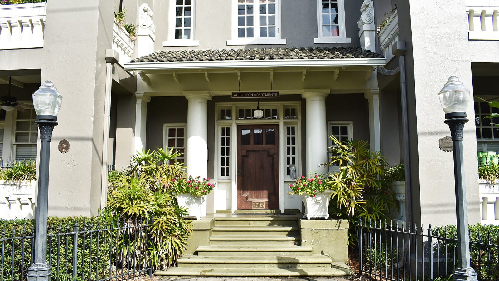 Steps and a covered porch leading to the entrance of a pale apartment building