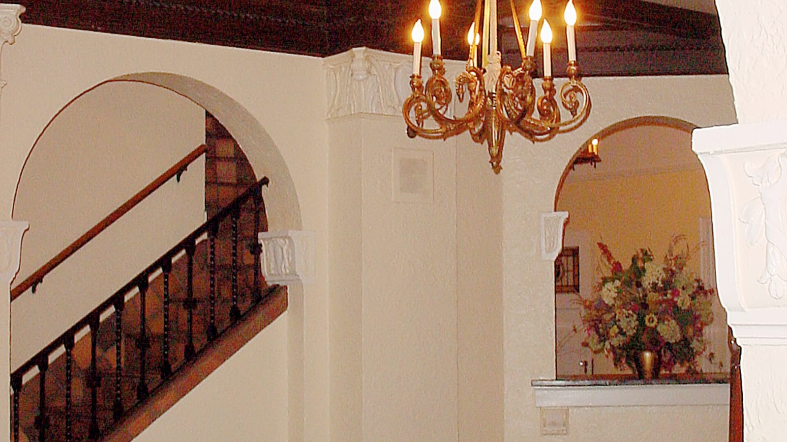 Apartment lobby with a chandelier, curved arch and wooden staircase