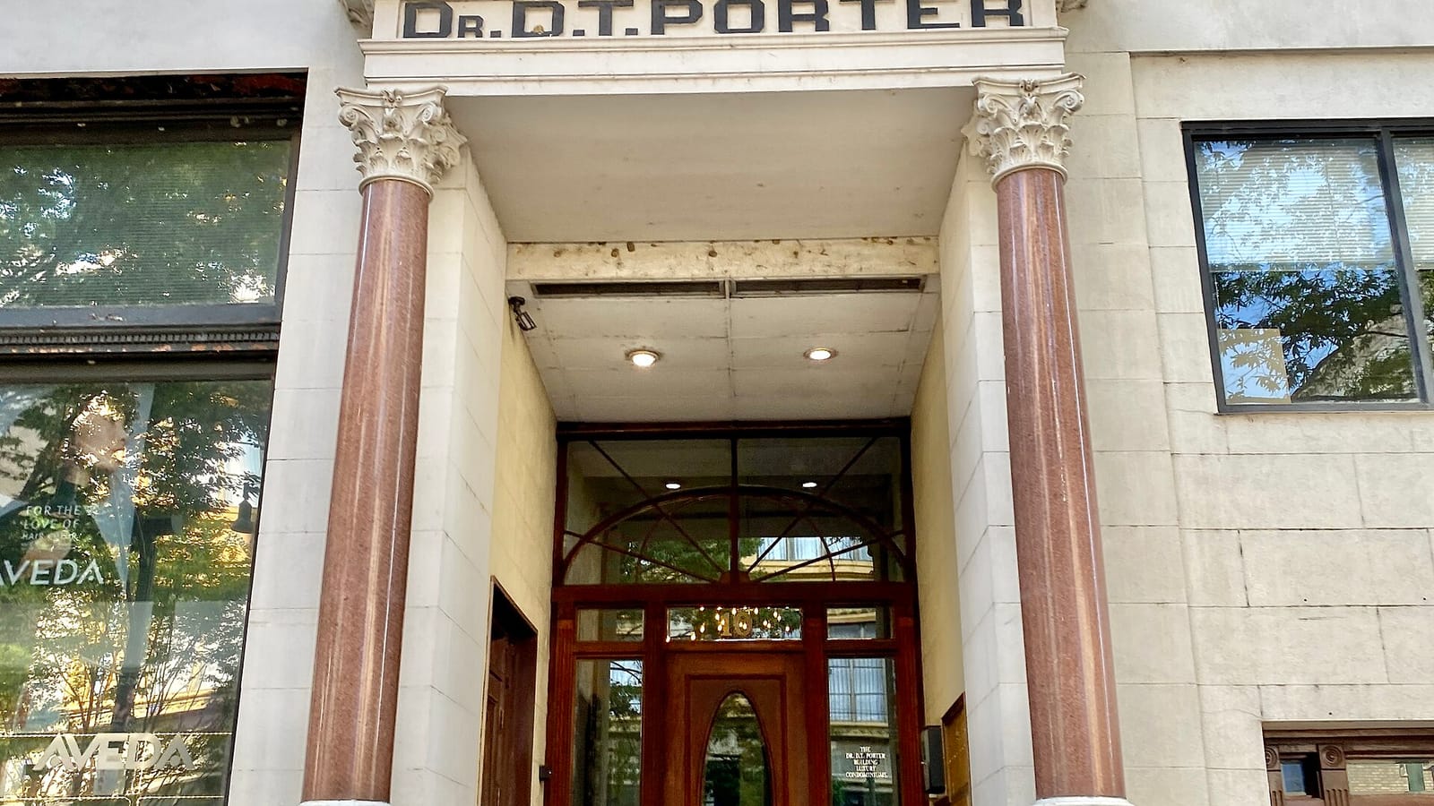 Recessed building entrance between stone columns beneath a carved name