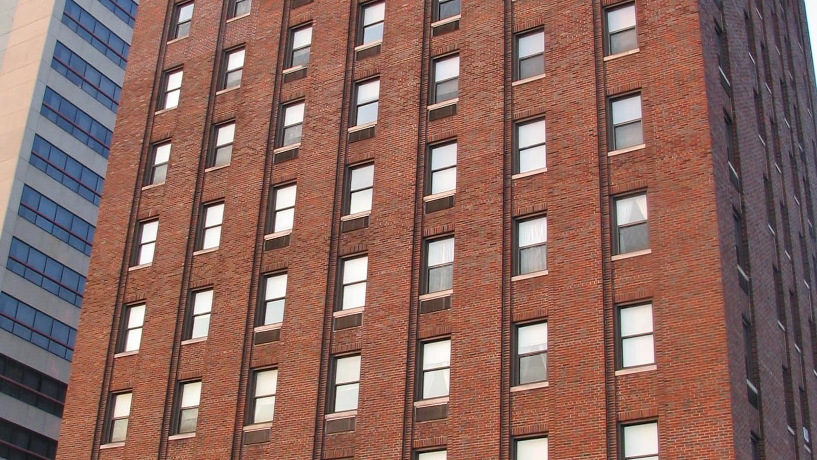 Red brick high-rise facade with narrow vertical window rows