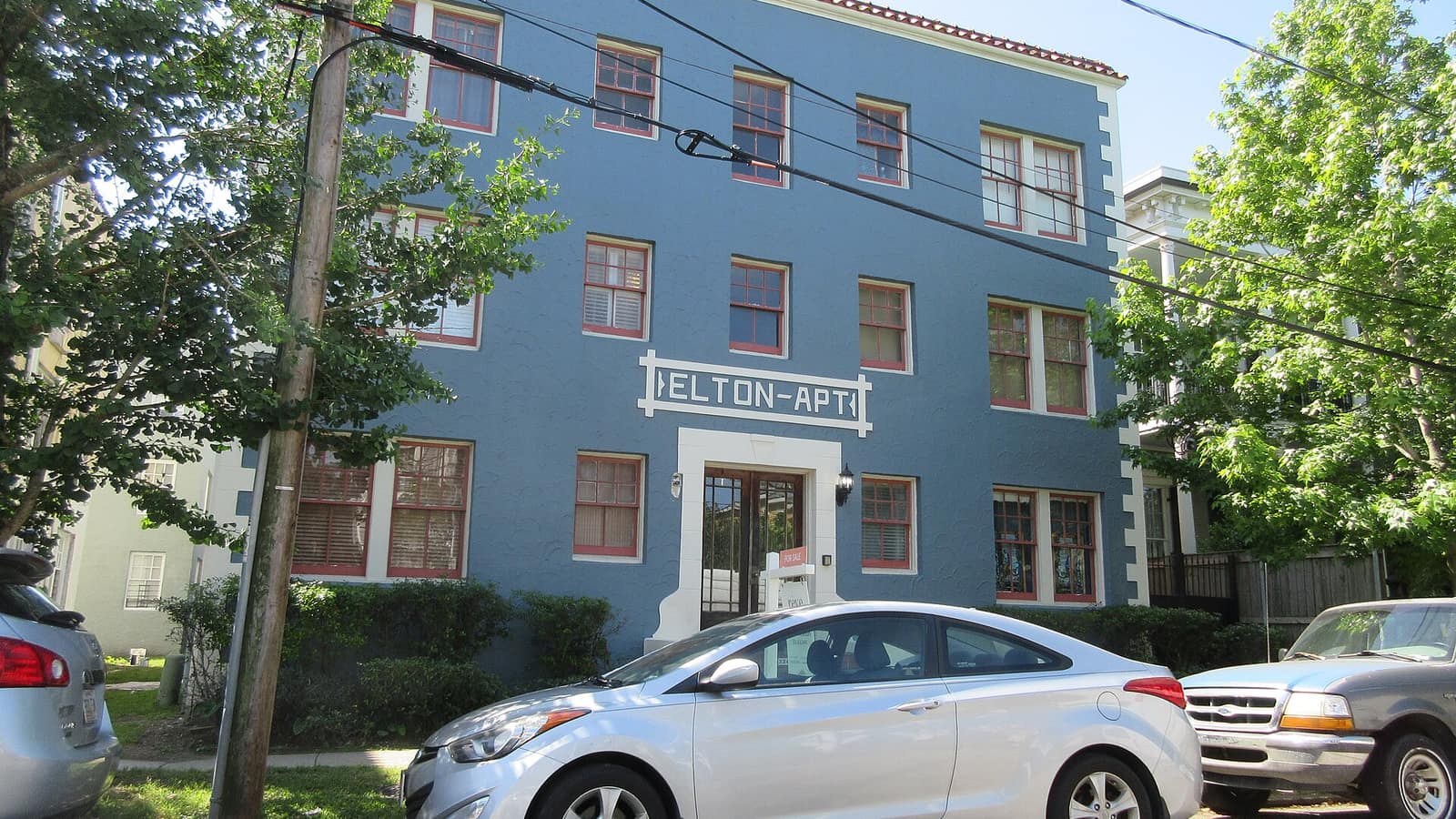 Blue apartment facade with pale window trim and a central door