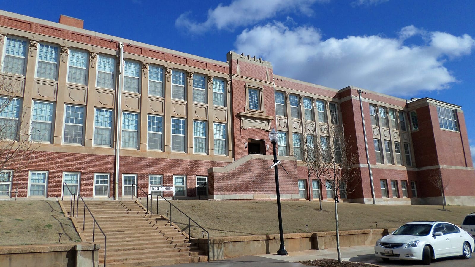 Large brick former school building with broad stairs and rows of tall windows