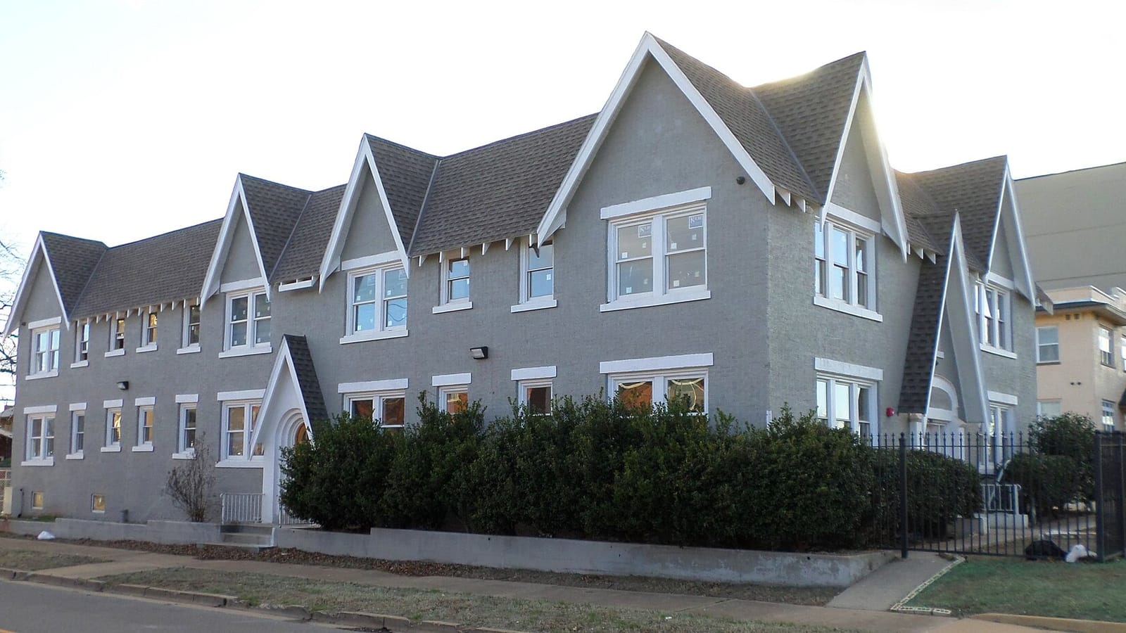Long gray apartment building with repeated steep gables and white window trim