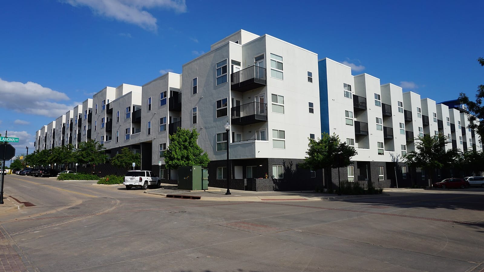White modern apartment block with dark balcony recesses at a street corner
