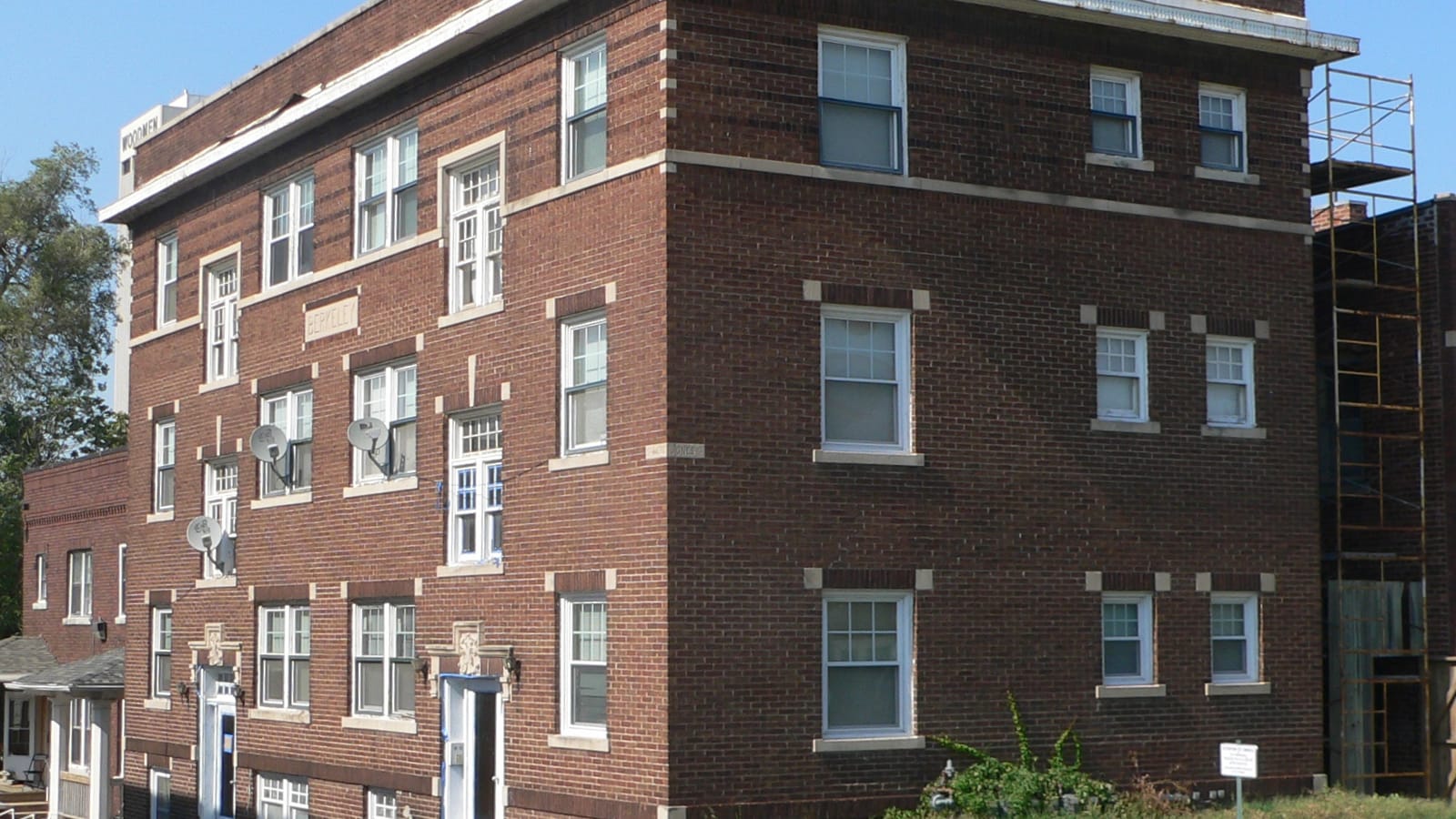 Corner of a low red brick apartment building with pale lintels above the windows