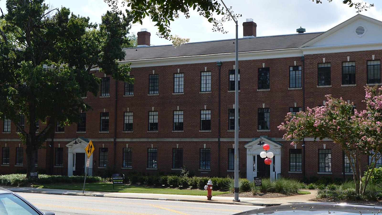 Brick apartment building with pale entrance trim beside a sidewalk