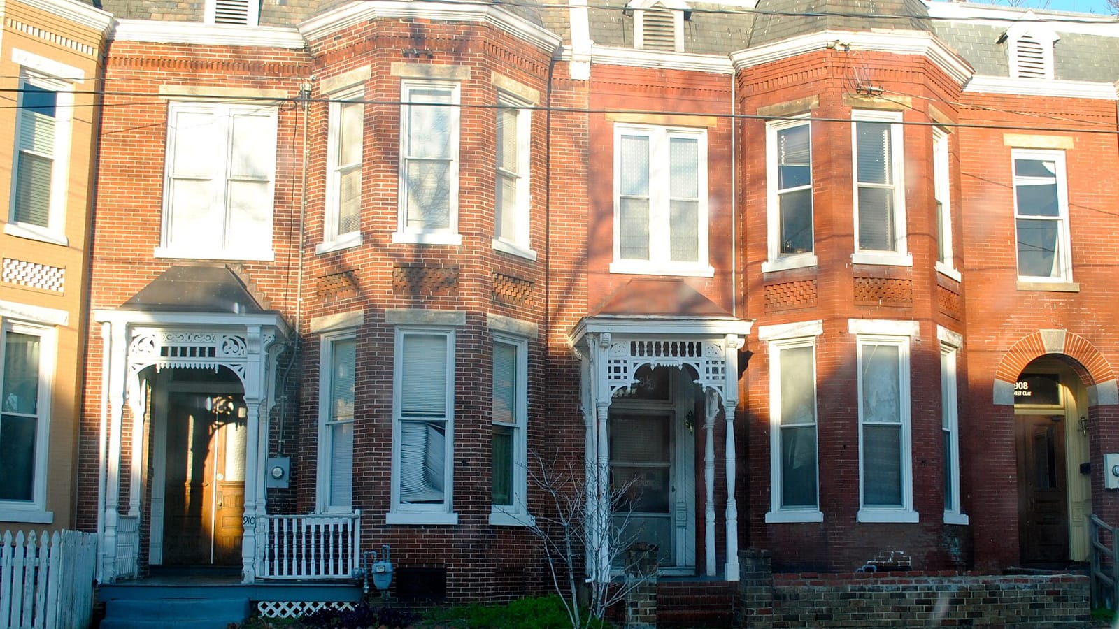 Red brick row houses with projecting bay windows and small covered entrances