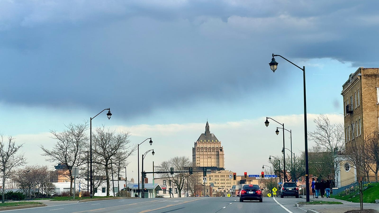 City street leading toward a tall tower beyond brick commercial buildings