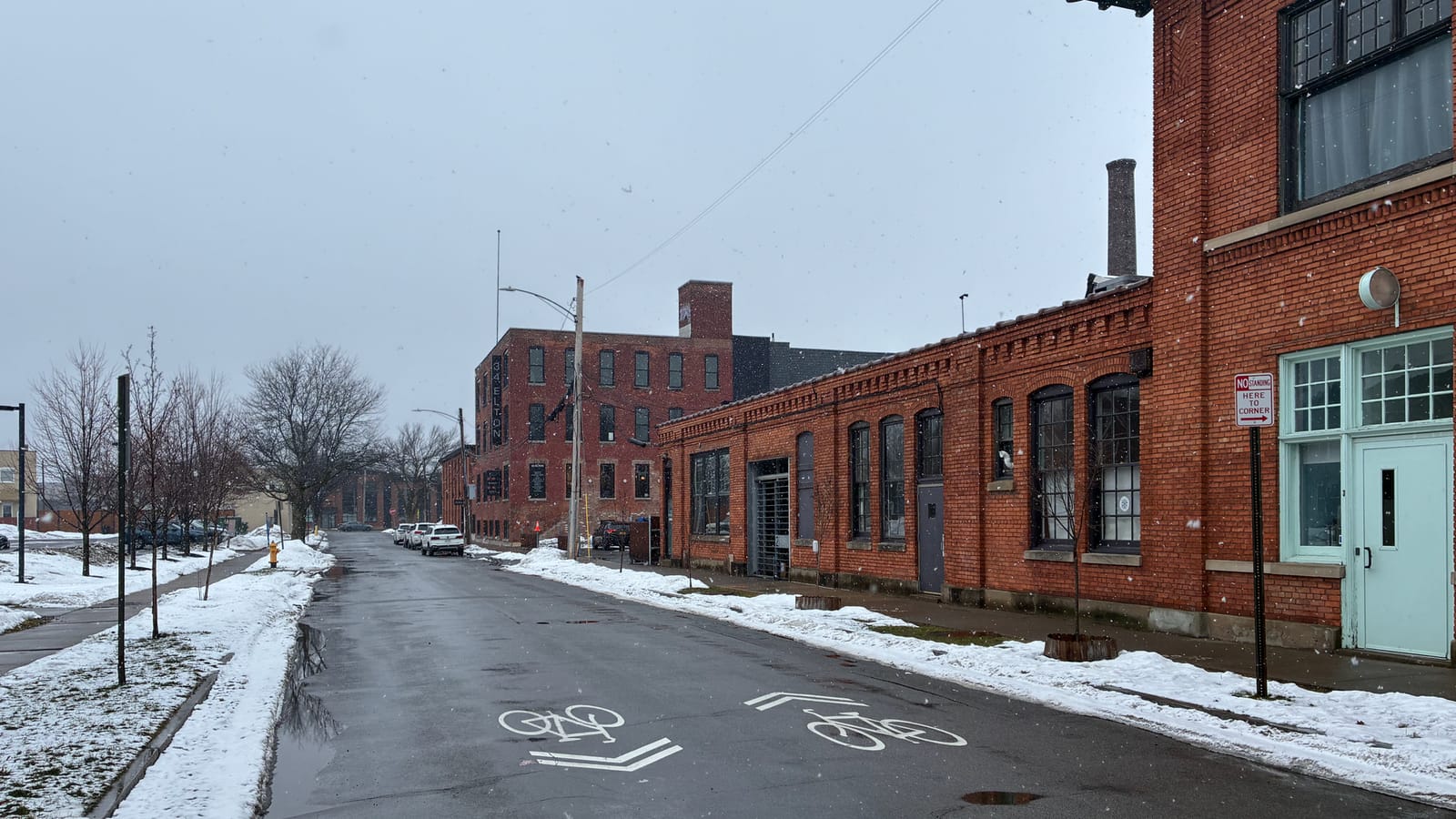Brick buildings and a bicycle lane along a snow-lined street