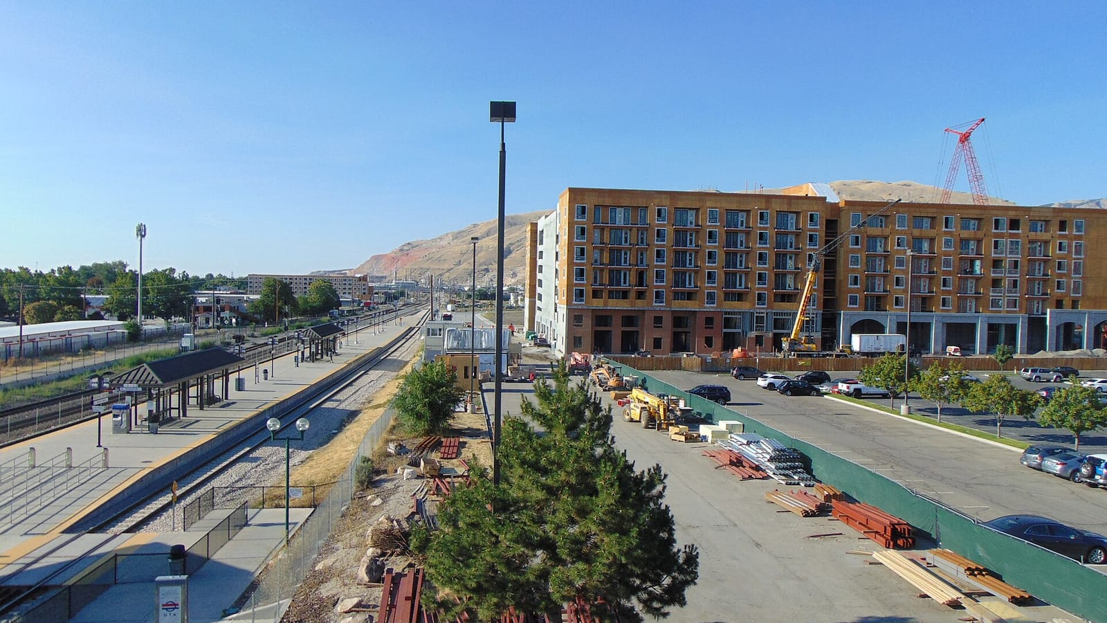 Rail platforms and parallel tracks beside a street and apartment construction