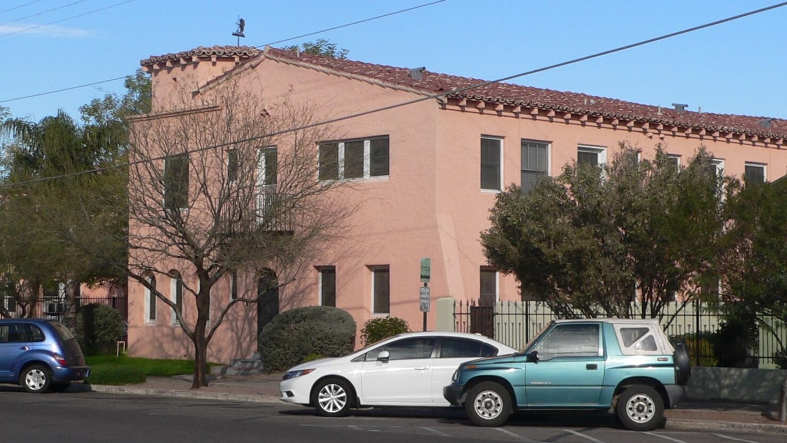 Peach stucco apartment building with a tiled roof at a street corner