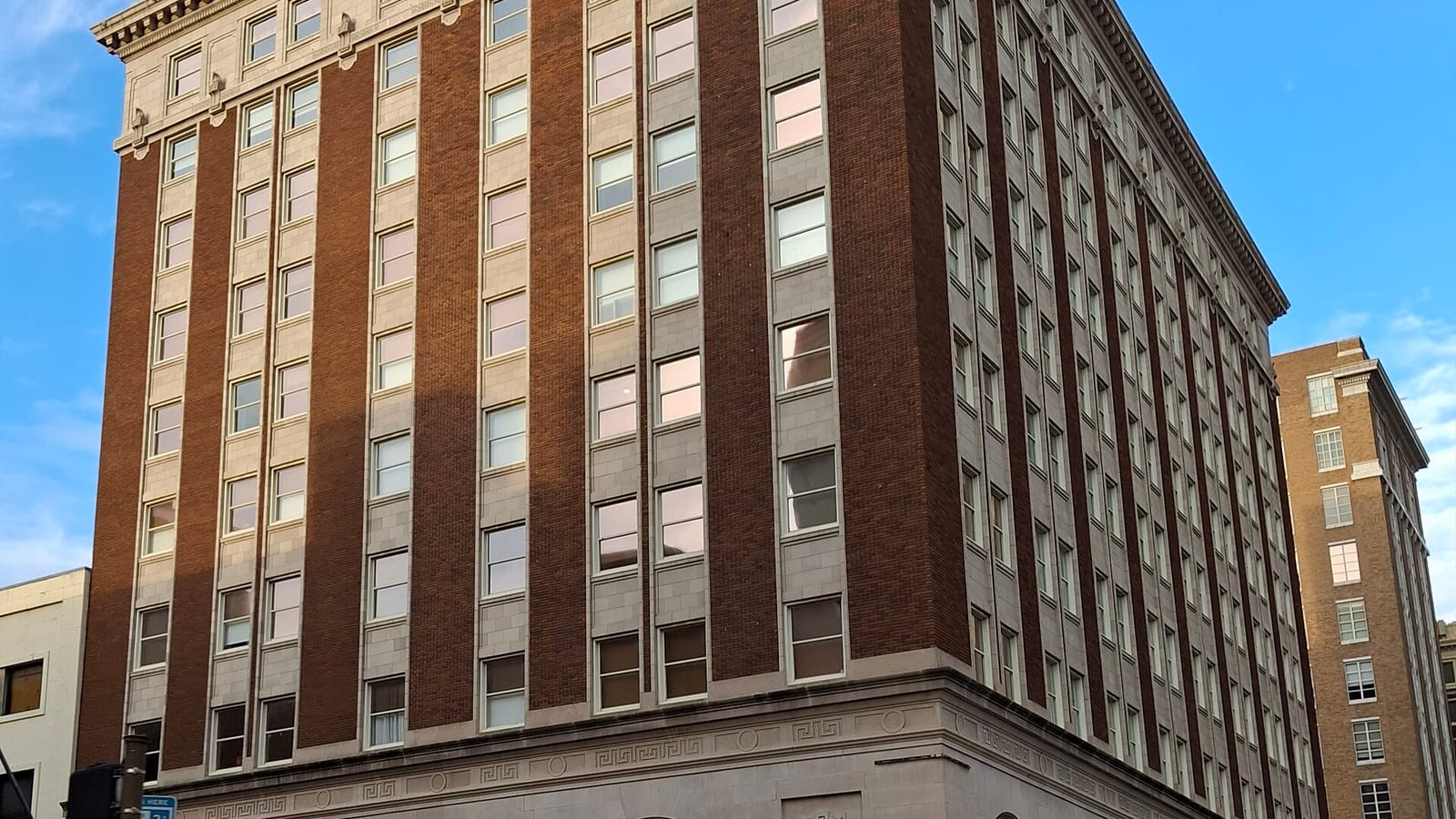 Red brick apartment facade with pale vertical trim and rows of windows