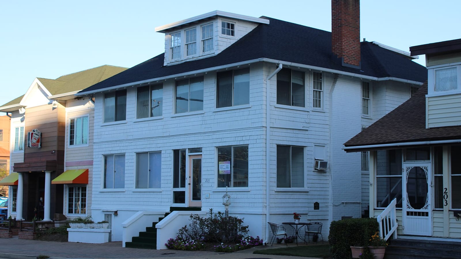 White two-story cottage with a broad enclosed porch