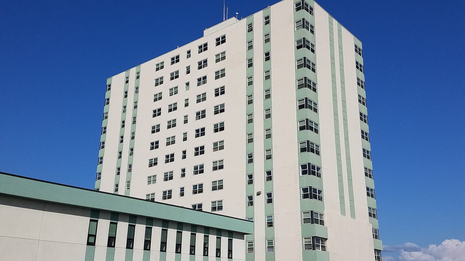 Pale apartment tower against a blue sky