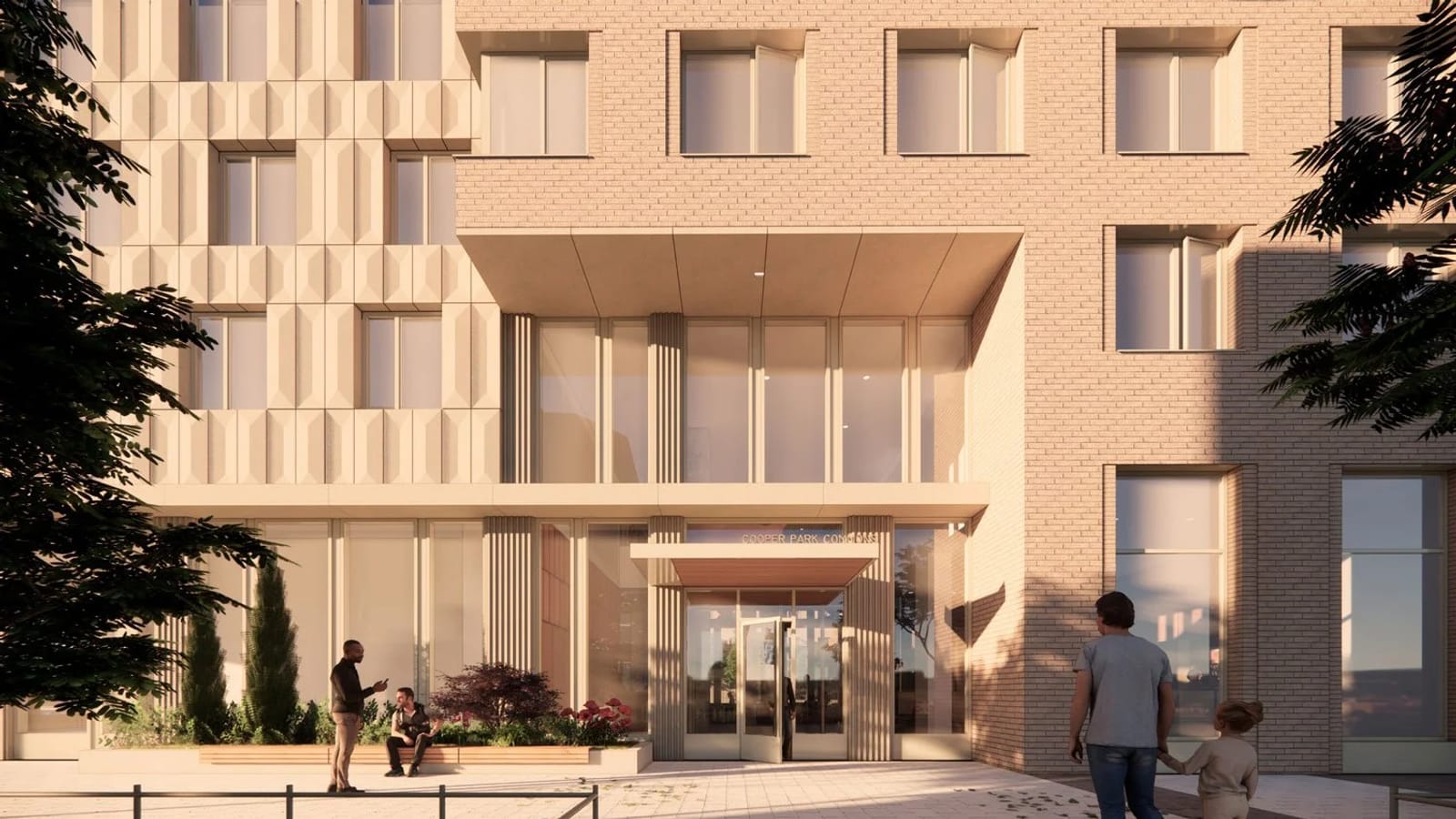 Rendering of a building entrance in warm low light: a glass door under a flat canopy with the words COOPER PARK COMMONS above it, a two-story glazed lobby front, tan brick and ribbed beige panels above, two people talking beside a planter and an adult walking with a child