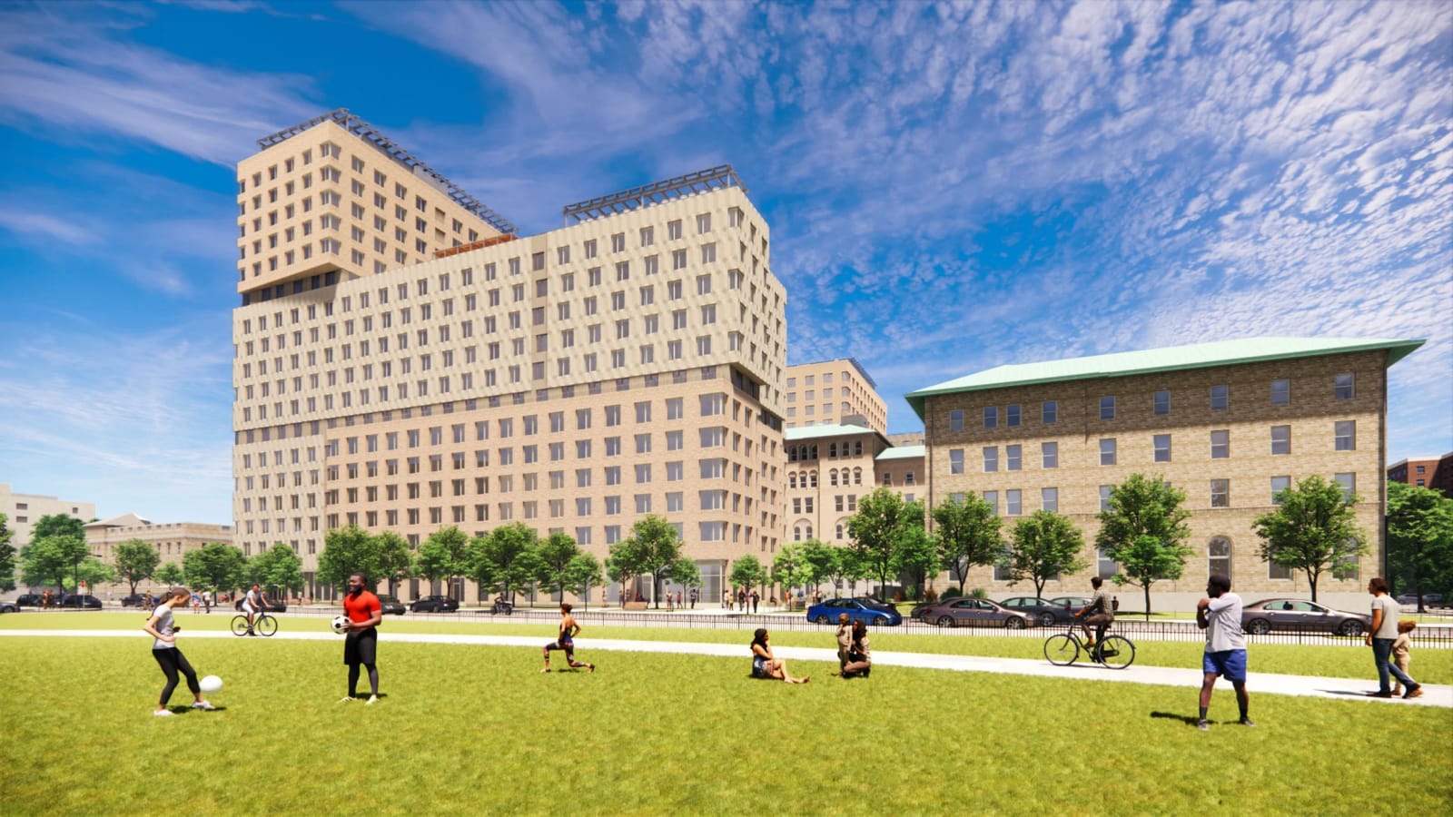 Rendering of a long apartment building in tan brick and beige panels with a taller tower section at its left end, seen across a park lawn where people kick a ball, sit on the grass and ride bicycles; a lower brick building with a green roof stands to its right