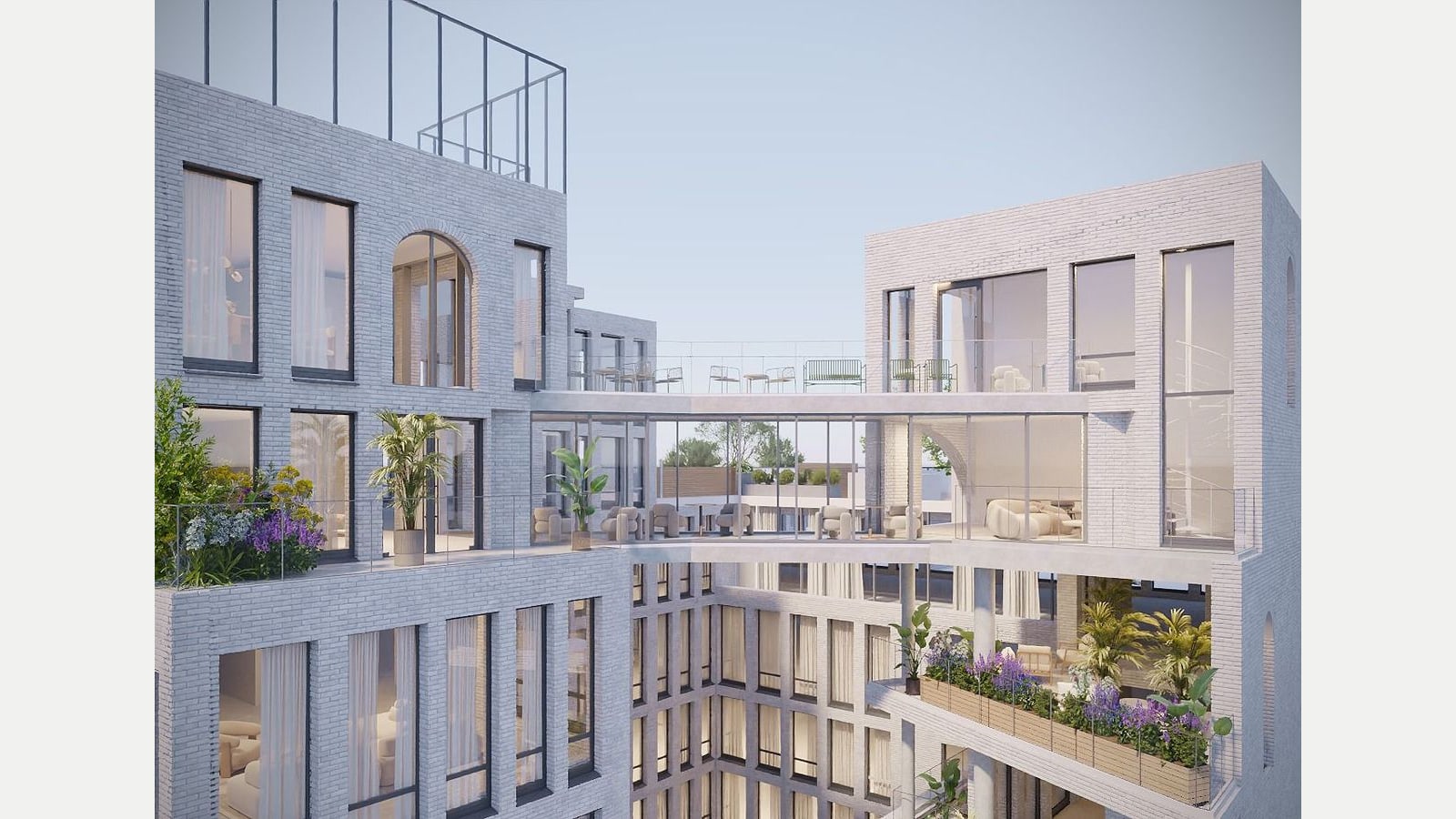 Rendering looking across an inner courtyard of pale gray brick wings with tall and arched windows, a glass-walled bridge with lounge chairs linking two wings, planted terraces with railings, and a metal frame on the roof