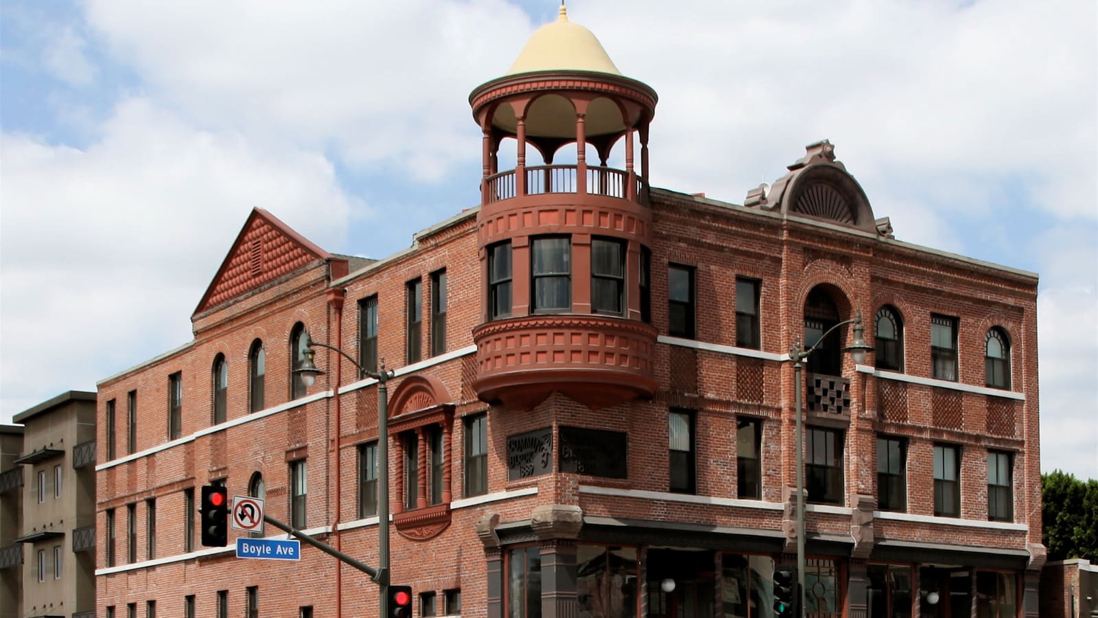 A three-storey red brick Victorian building with a domed corner turret at a street corner signed Boyle Ave