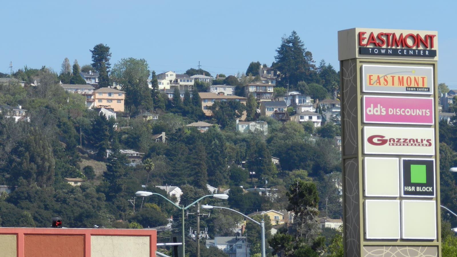 A tall Eastmont Town Center sign in front of a wooded hillside covered with houses