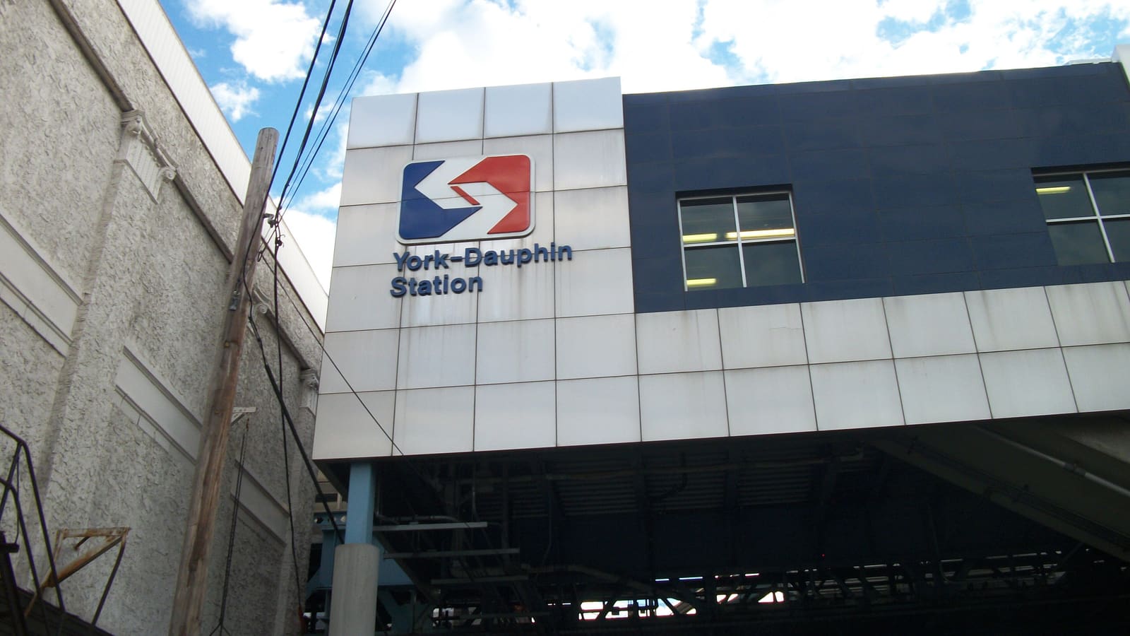 The white and navy panelled wall of an elevated railway station with a SEPTA logo and the words York-Dauphin Station