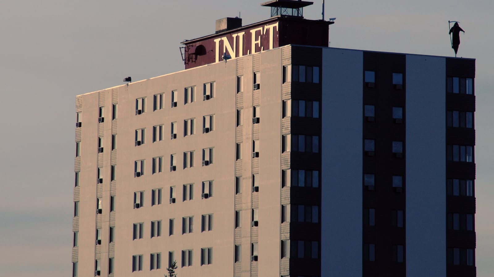 Brown apartment tower with rows of windows and a rooftop sign
