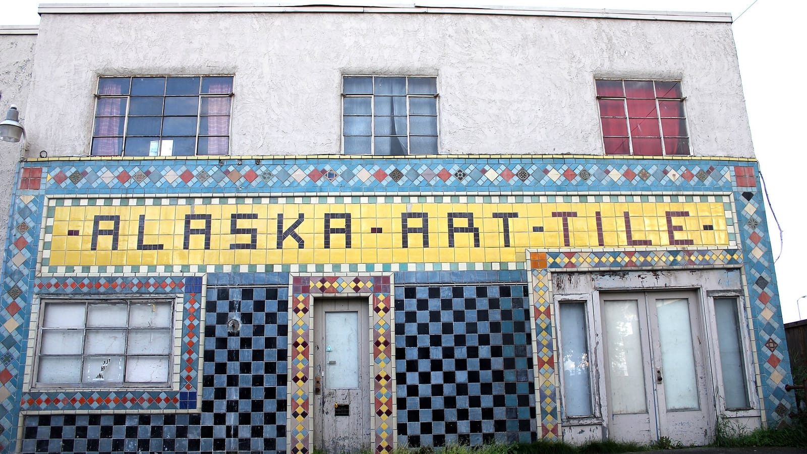 Small building with a colorful tile facade and old business name