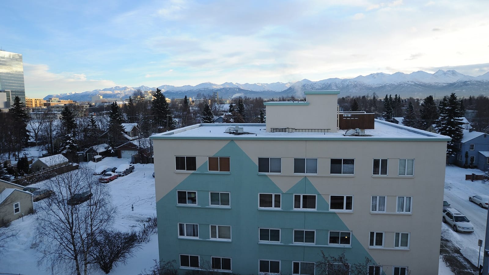 Apartment building painted with a mountain pattern amid snow-covered streets