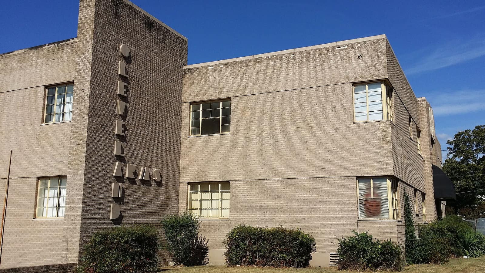 Pale brick apartment building with a vertical name sign