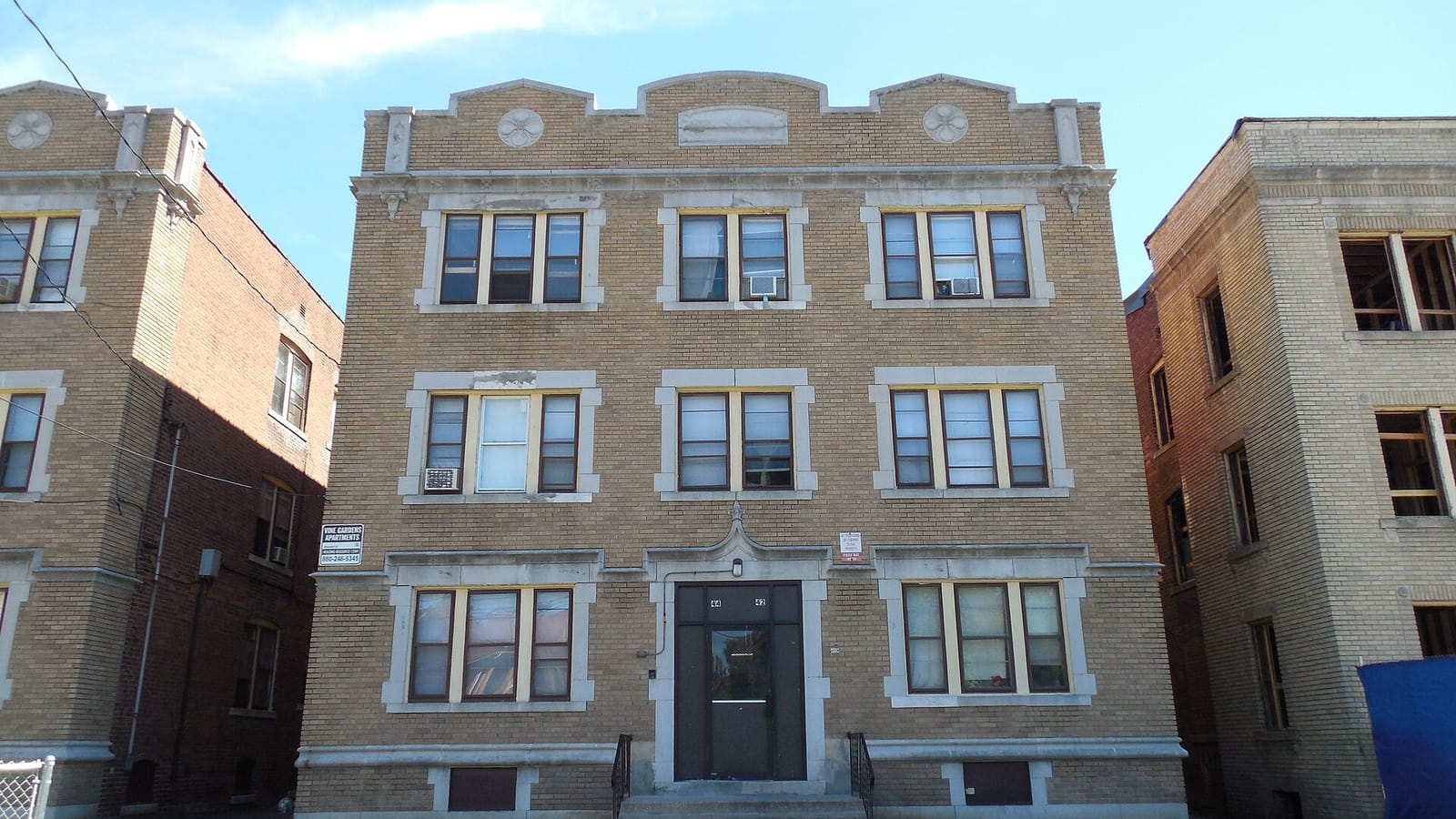 Tan brick apartment facade with decorative pale trim