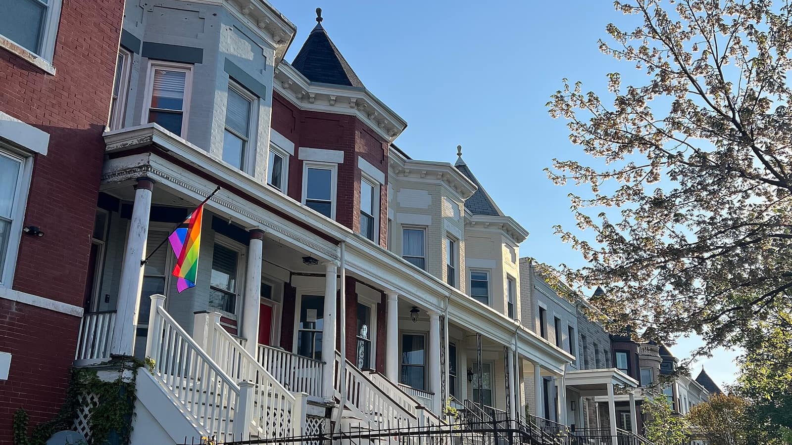 Rowhouses with front porches beside a sidewalk